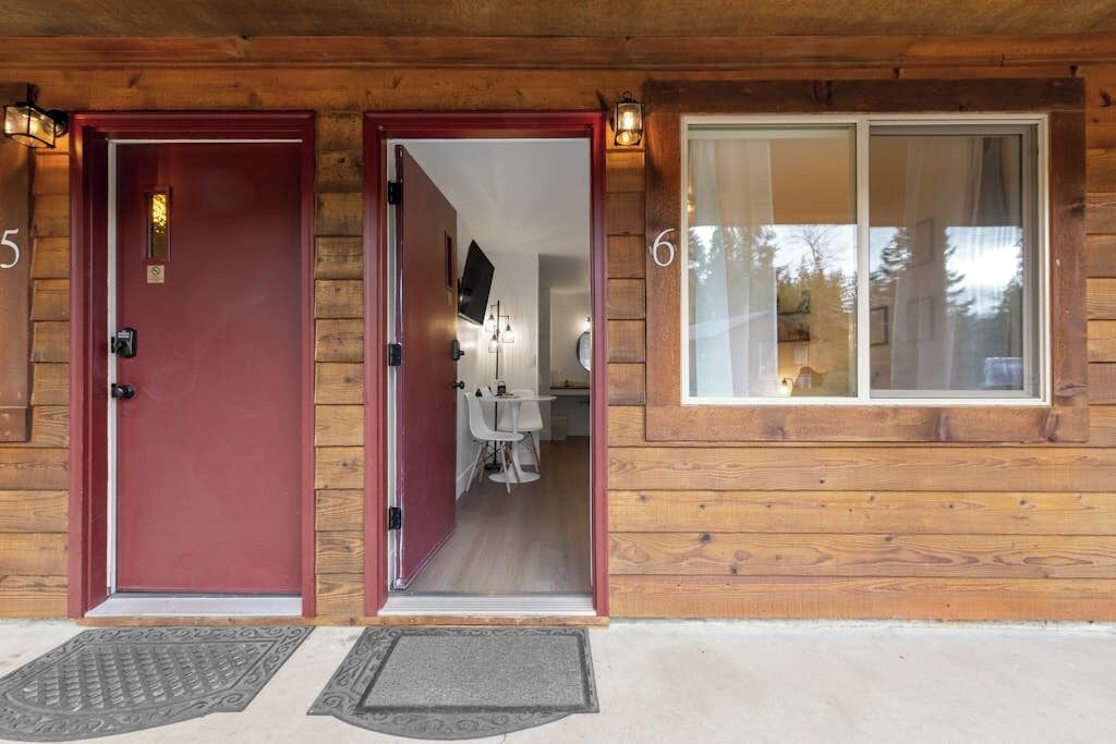 Un bâtiment en bois avec deux portes, une rouge et une blanche, et une fenêtre donnant sur l’extérieur.