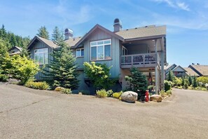 A two-story house with a balcony, surrounded by greenery and a driveway. - 2BR mountainview condo with balcony & pool (Ronald)
