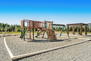 A playground with a wooden climbing structure and a swing set. - 2BR mountainview condo with balcony & pool (Ronald)