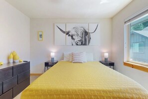 A bedroom with a bed, bedside tables, a window, and a wall-mounted artwork of a bull. - 2BR mountainview condo with balcony & pool (Ronald)