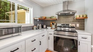 Una cocina moderna con armarios blancos, electrodomésticos de acero inoxidable y vistas al exterior.