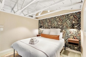 A bedroom with a bed, a nightstand, and a wall with a floral pattern. - Cabins 1BR Lakefront - Dock - Deck - Firepit (Fall City)