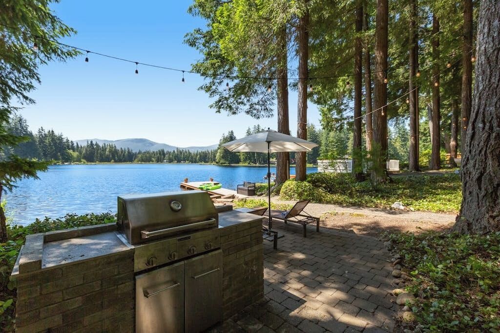 Eine Außenpatio mit Grill, Lounge-Stühlen und Seeblick.