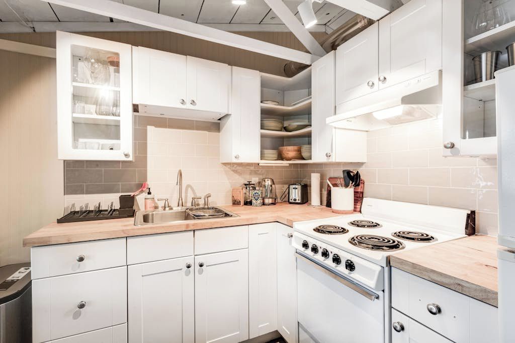 A kitchen with white cabinets, a stove, and a sink.