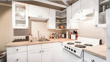 A kitchen with white cabinets, a stove, and a sink.