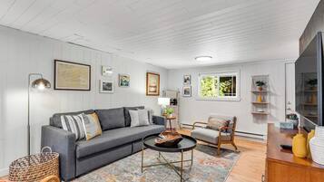 A living room with a grey sofa, a round coffee table, and a patterned rug.