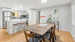 Una cocina moderna con una isla central, taburetes de bar y una mesa de comedor con sillas.