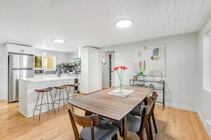 Uma cozinha moderna com uma ilha central, banquetas de bar e uma mesa de jantar com cadeiras.