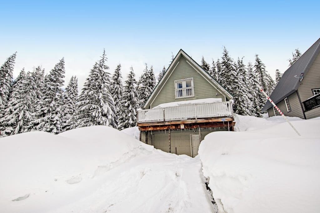 Une maison dotée d’un balcon, entourée d’arbres couverts de neige.