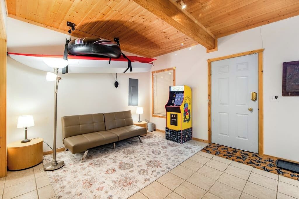 A room with a sofa, a lamp, a punching bag, and a video game machine.