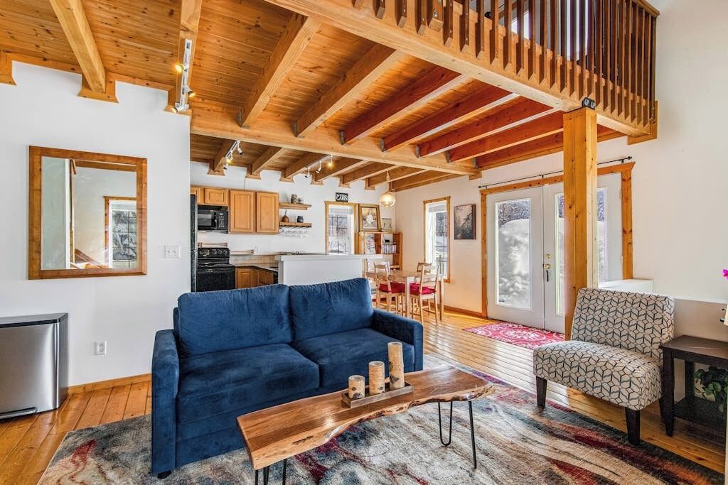 A spacious living area with a blue sofa, a wooden coffee table, and a patterned armchair.
