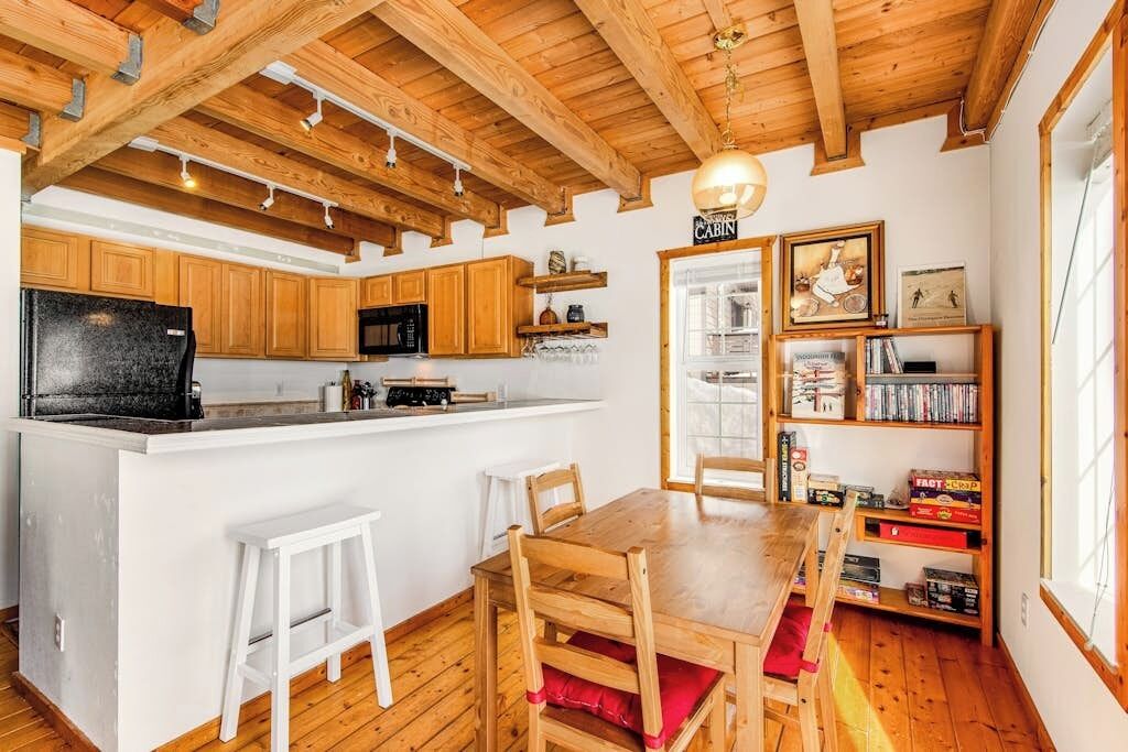 Interior de una cabaña con cocina, comedor y estantería.