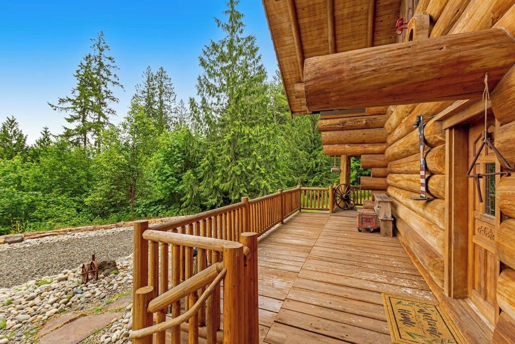 A wooden log cabin with a wooden deck and a metal railing.
