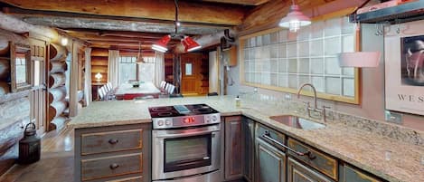 A kitchen with a central island, stainless steel appliances, and a wooden ceiling.