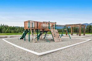 A playground with a wooden climbing structure, slides, and a picnic area. - 3 BR Cozy Mountain Getaway, New Build (Ronald)