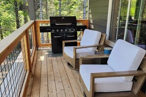 A wooden deck with a grill and two white cushioned chairs. - 3 BR Cozy Mountain Getaway, New Build (Ronald)