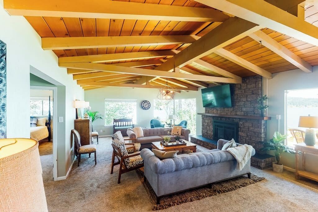 A spacious living room with a fireplace, wooden ceiling beams, and comfortable seating.