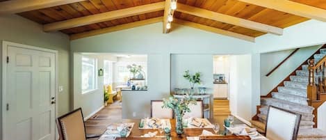 Un comedor con techo de madera, una escalera y vistas a la cocina.