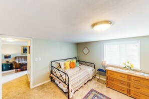 Une chambre à coucher avec un lit, une commode et une fenêtre équipée de stores.