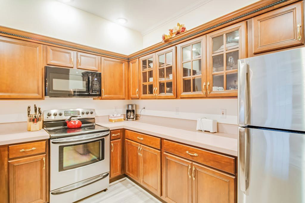 Una cocina con gabinetes de madera, un refrigerador de acero inoxidable, un microondas y un horno.