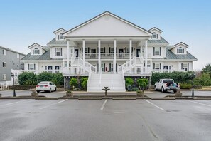 Un grand bâtiment à deux étages, doté d’un escalier central menant à un balcon, et entouré d’un parking.