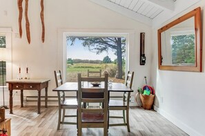 Een eethoek met een tafel en stoelen, een raam met uitzicht op de omgeving, en een deur naar buiten.