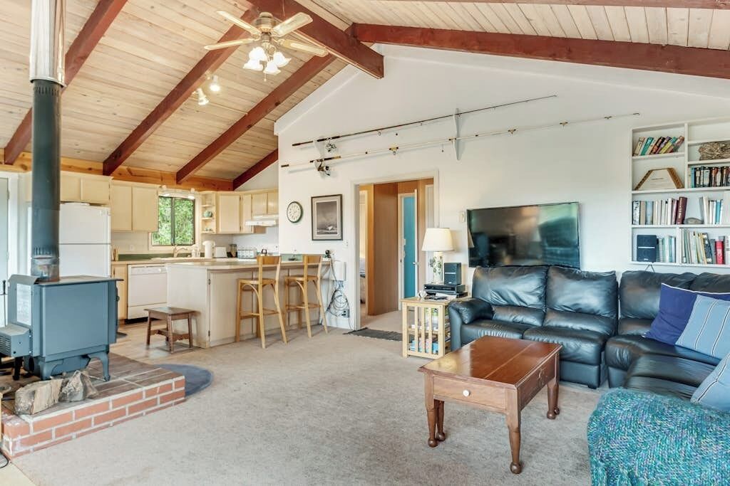 A spacious living area with a fireplace, a leather sofa, and a dining area with wooden chairs.