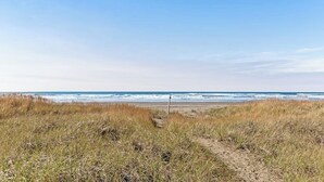 Ein Strandweg, der zum Meer führt, bei blauem Himmel.