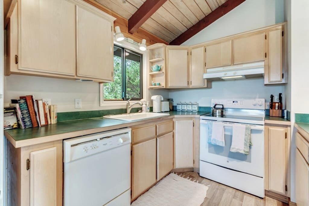 A kitchen with wooden cabinets, a dishwasher, an oven, and a window providing natural light.