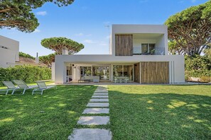 A modern two-story house with a covered patio, outdoor seating, and a well-maintained lawn.