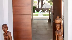 A modern entrance with a sliding door, a concrete pathway, and two wooden sculptures. - Villa Playa de Roche: private pool, 1000m² garden, 2 en suite bathrooms (Roche)