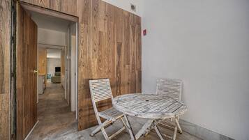 Een kamer met een houten wand, een ronde tafel en twee stoelen.