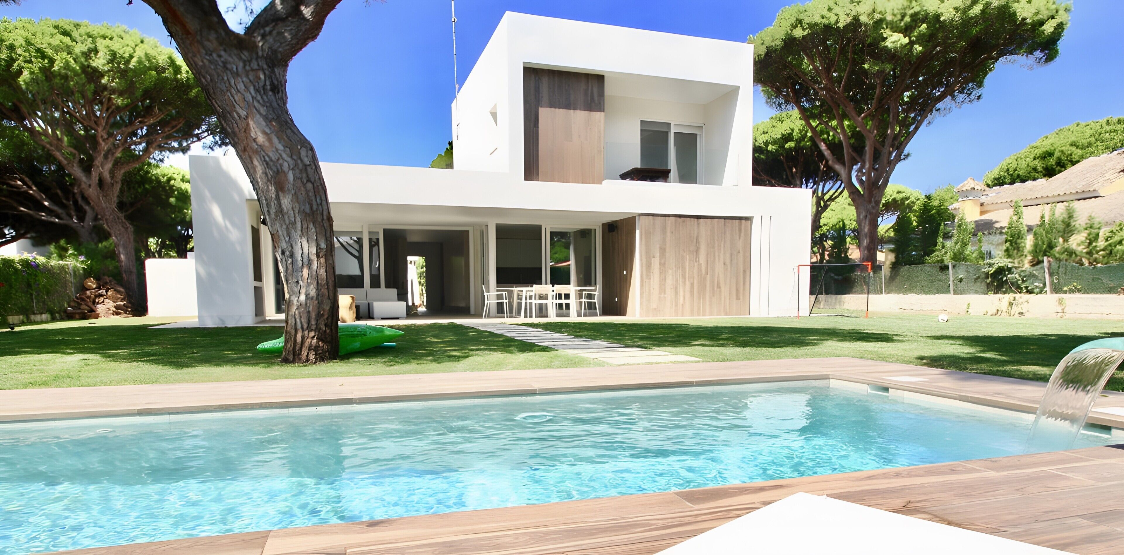 A modern two-story house with a swimming pool, outdoor seating, and a well-maintained lawn.