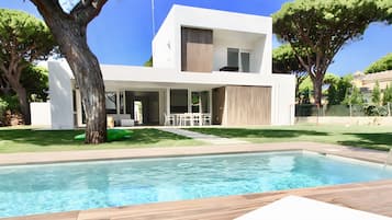 A modern two-story house with a swimming pool, outdoor seating, and a well-maintained lawn.