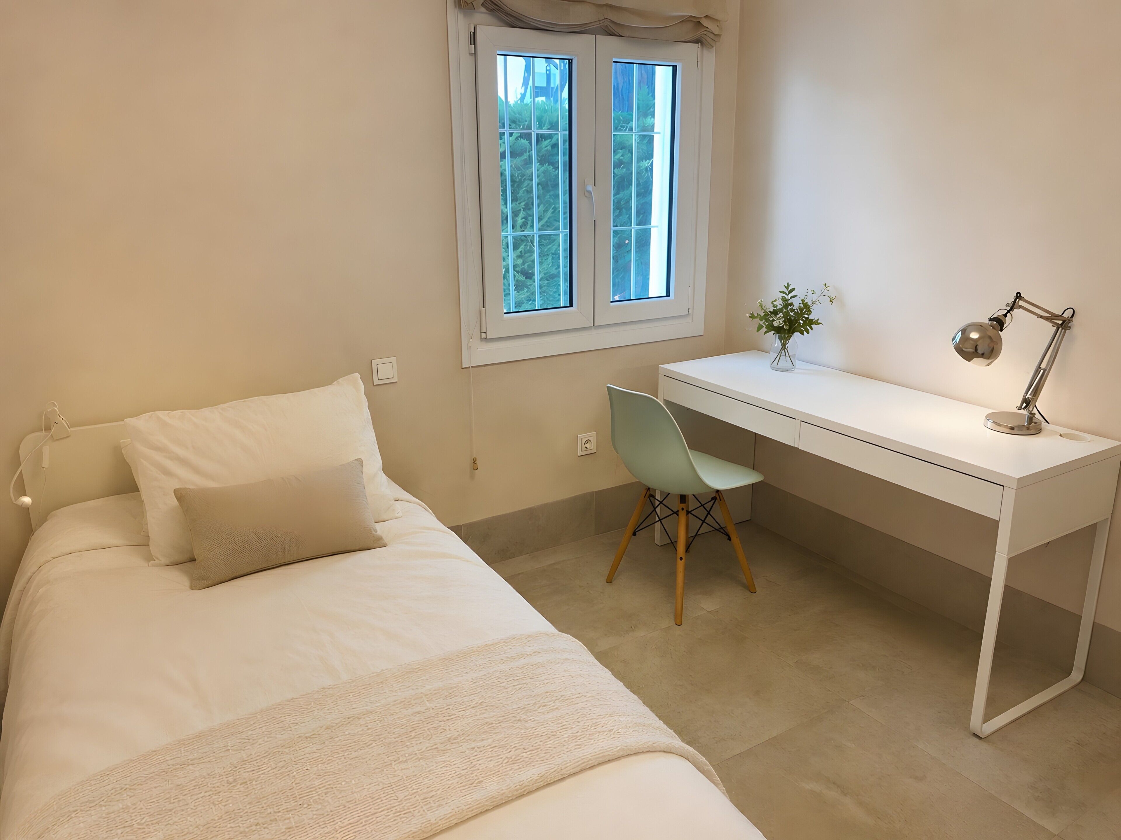 A bedroom with a bed, a desk, and a chair.