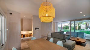 A modern living room with a wooden dining table, light blue chairs, a grey sofa, and a large woven light fixture. - Villa Playa de Roche: private pool, 1000m² garden, 2 en suite bathrooms (Roche)