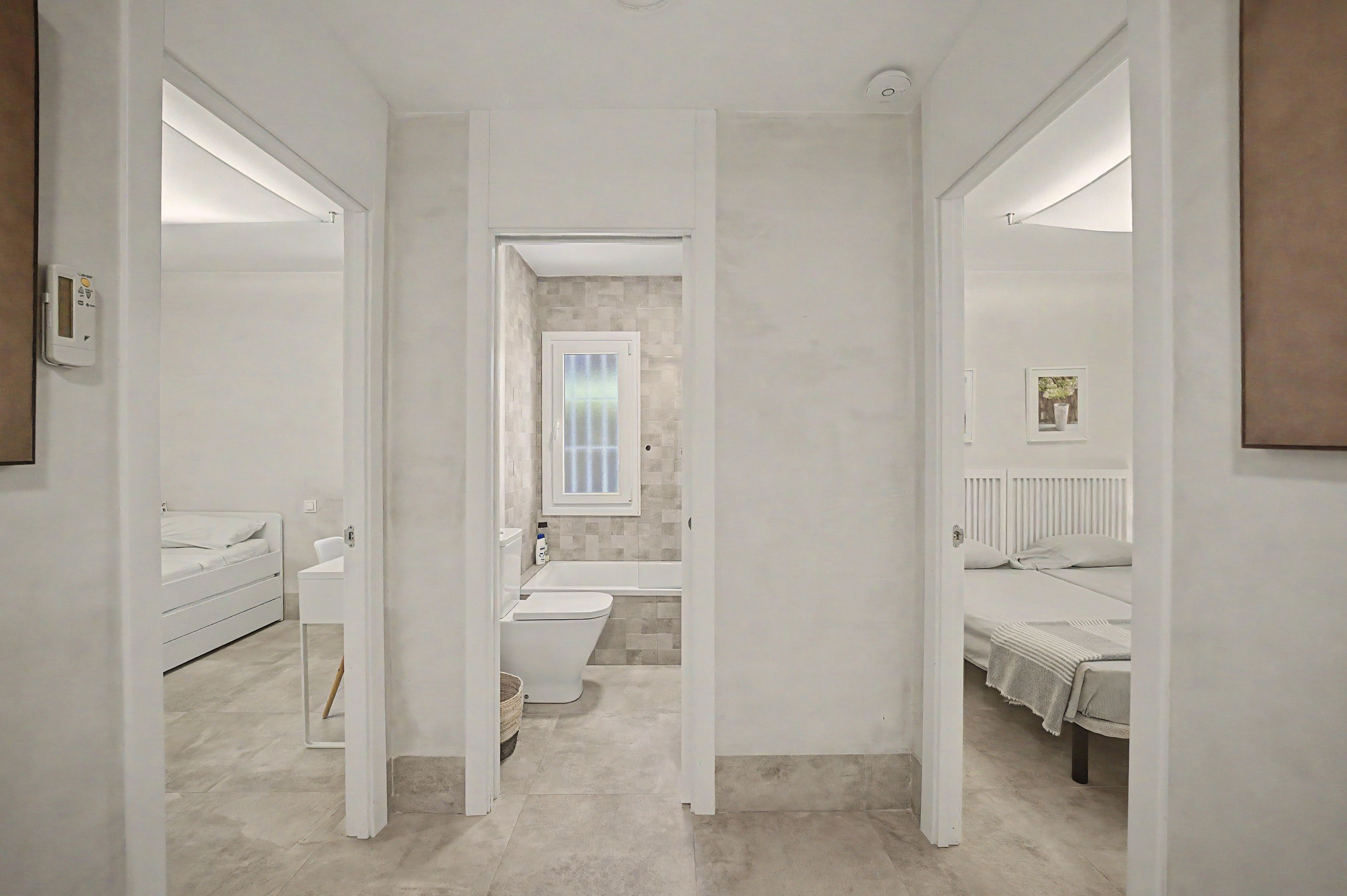 Un baño moderno con inodoro, bidé y bañera. Hay un espejo en la pared y una pequeña ventana sobre la bañera.