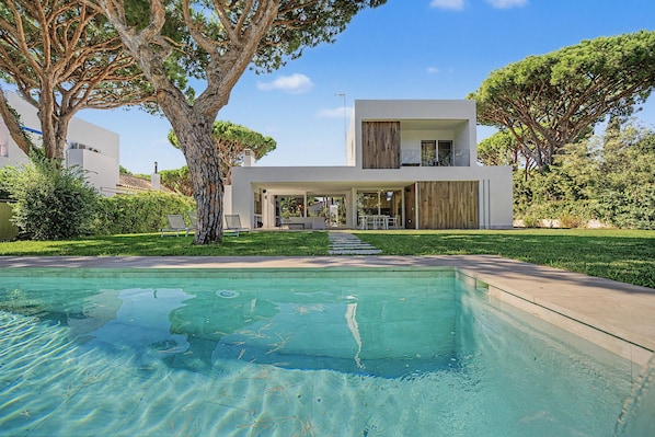 A modern two-story house with a swimming pool in the foreground.