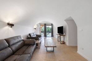Una sala de estar moderna con un sofá de cuero, una mesa de centro y un televisor sobre un mueble de madera.
