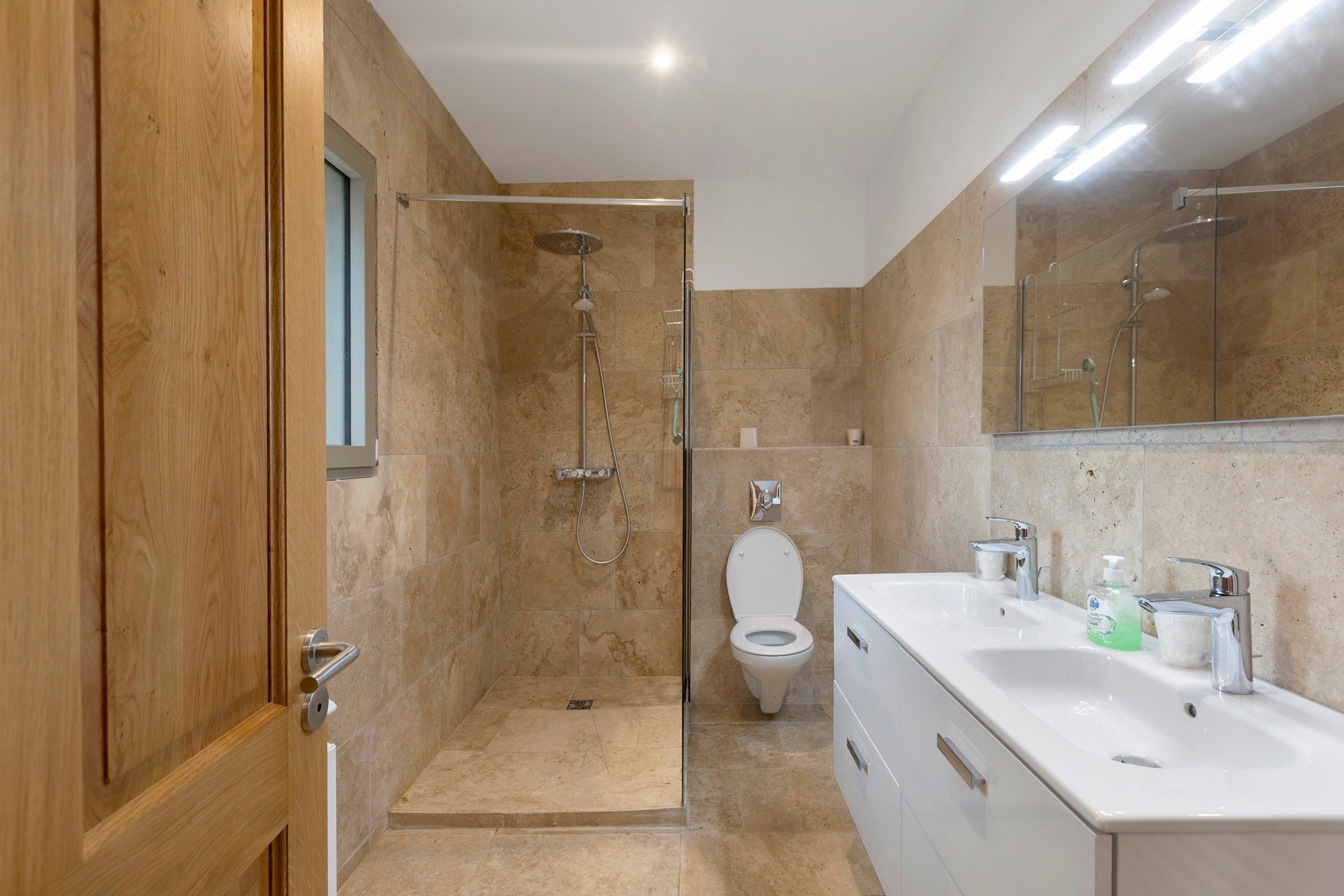 A modern bathroom with a shower, toilet, and a sink with a mirror.