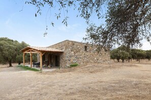 A stone building with a covered patio and outdoor seating. - Holiday Home 'La Bergerie De L'Ostriconi' with Mountain View, Shared Pool and Air Conditioning (Palasca)