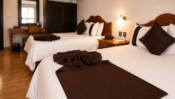 Habitación de hotel con dos camas, un escritorio, un espejo y un equipo de aire acondicionado.
