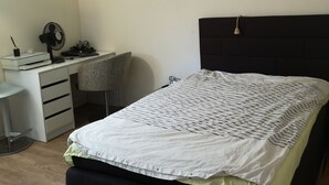 Een slaapkamer met een bed, een bureau en een stoel.