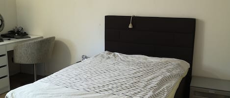 A bedroom with a bed, a desk, and a chair.