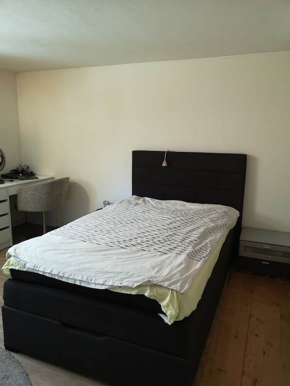 A bedroom with a bed, a desk, and a chair.
