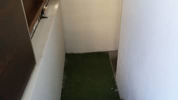 Eine enge Treppe mit grünen Teppichstufen führt zu einer Zwischenebene.