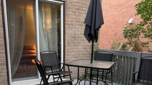 A deck with a table and chairs, a sliding glass door, and a brick wall. - The Belleville Retreat-Wifi, Quiet Private Patio (Belleville)