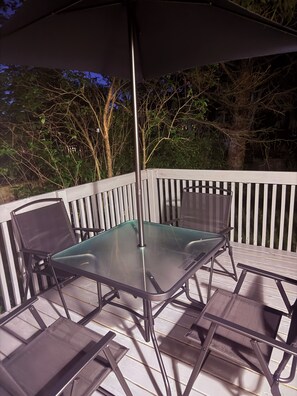 An outdoor patio with a glass table and chairs, surrounded by a white railing. - The Belleville Retreat-Wifi, Quiet Private Patio (Belleville)