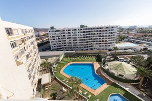 Et hotel med flere etager, en pool på taget og havudsigt.