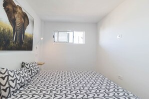 A bedroom with a bed, a window, and a wall-mounted picture of an elephant. - Blue sky:  ocean view & 5 min to Jumbo (Playa del Ingles)